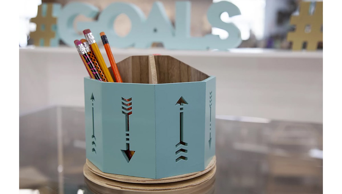 A teal wooden pen holder with pencils in it. A teal wooden pen holder with pencils in it.