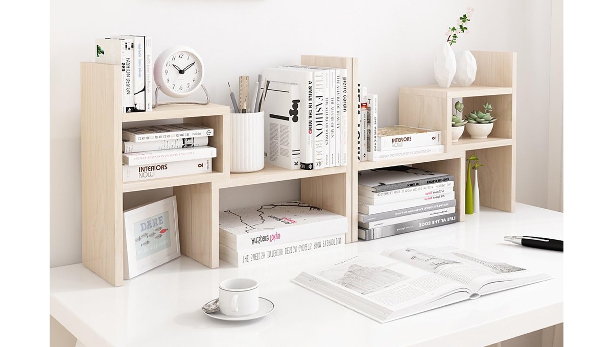 A beige Jerry and Maggie Desktop Office Organizer on a desk behind a cup and saucer, an open book and a pen. A beige Jerry and Maggie Desktop Office Organizer on a desk behind a cup and saucer, an open book and a pen.